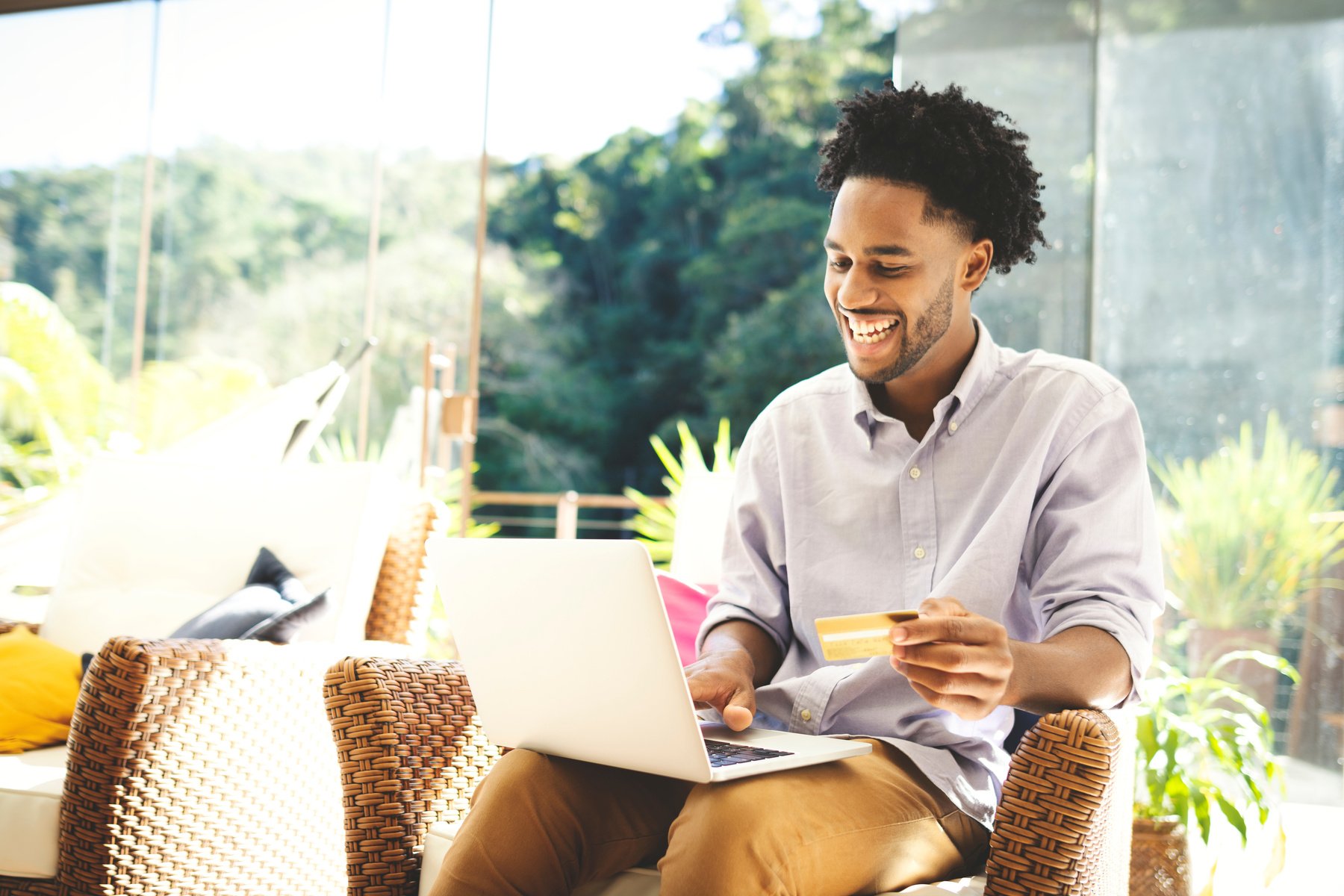 Young man using laptop, cell phone and credit card